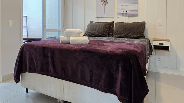 Quarto com cama, ventilador de teto, janela e obras de arte na parede.