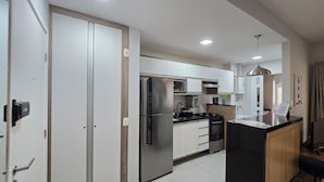 Uma cozinha moderna com eletrodomésticos de aço inoxidável, armários brancos e bancada em ilha preta.
