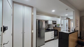 Une cuisine moderne dotée d’appareils électroménagers en acier inoxydable, de meubles blancs et d’un îlot central au comptoir noir.