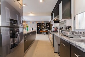 A modern kitchen with stainless steel appliances, a granite countertop, and a central island with seating. - Two Roma Norte Condos with City Views & Workspace (Ciudad de México)