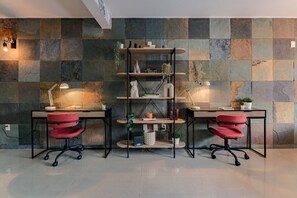 A modern office space with two desks, red office chairs, and a central shelving unit. - Two Roma Norte Condos with City Views & Workspace (Ciudad de México)