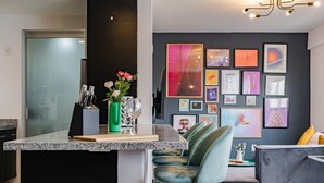 A modern kitchen with a granite countertop, a green vase with flowers, and a wine glass. - Two Roma Norte Condos with City Views & Workspace (Ciudad de México)