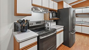 Una cocina moderna con electrodomésticos de acero inoxidable, armarios de madera y un microondas integrado.