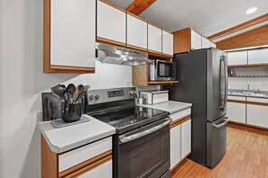Een moderne keuken met roestvrijstalen apparatuur, houten kastjes en een ingebouwde magnetron.