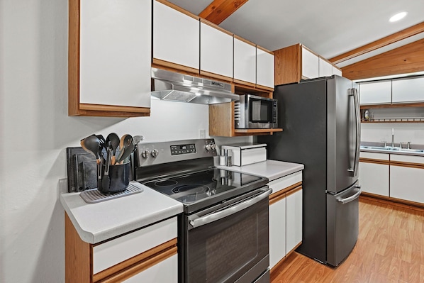 A modern kitchen with stainless steel appliances, wooden cabinets, and a built-in microwave.