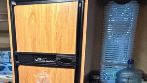 A compact kitchen with a wooden cabinet, a water dispenser, and a toaster.
