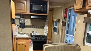 A compact RV kitchen with a microwave, stove, and seating area. - Camping without the work ! Beautiful sunsets in a tranquil setting . Glamping! (Matlock)