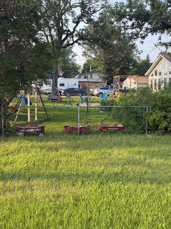 A grassy area with playground equipment, a swing set, and a red boat.