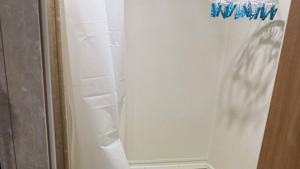 A small bathroom with a white bathtub, a toilet, and a shower curtain.
