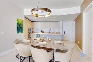 A modern dining area with a central island, chairs, and a pendant light. - 2BR Ocean Views & Modern Comfort (Hollywood)
