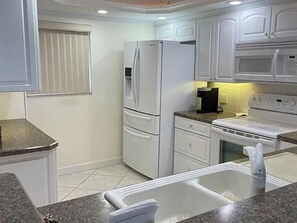 Una cocina con electrodomésticos blancos, que incluyen un refrigerador, microondas y estufa.