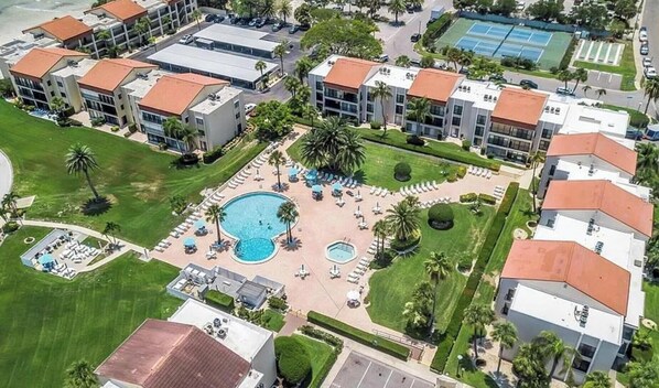 Un hotel de varios pisos con una piscina central rodeada de tumbonas y palmeras.