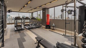 Ein Fitnessraum mit Laufbändern, einer Bank, einem Boxsack und Gewichten.