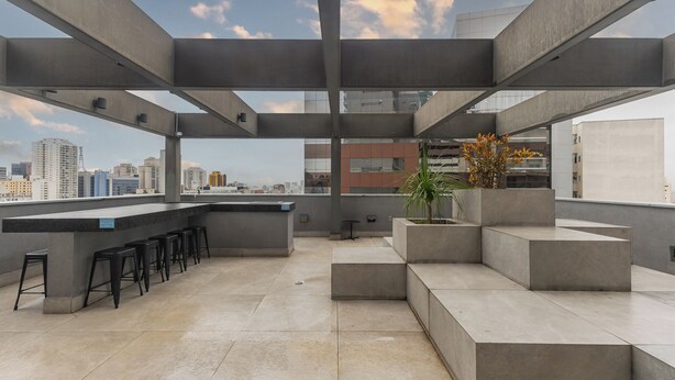 Eine Dachterrasse mit Bar, Sitzgelegenheiten und Blick auf die Stadt.