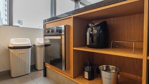 Eine moderne Küche mit Backofen, Kaffeemaschine und einem Edelstahl-Eimer.