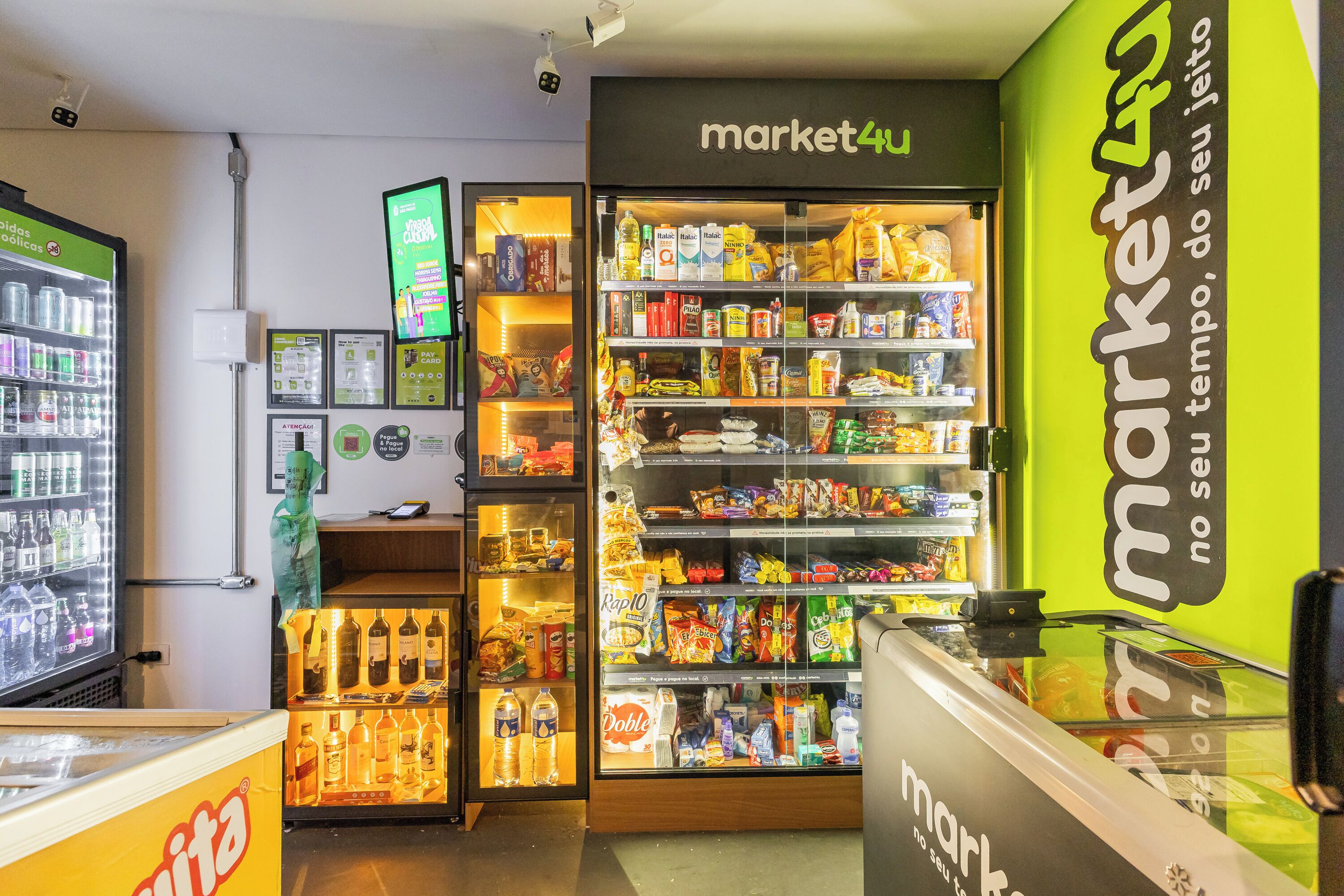 Interior de um supermercado com diversos produtos nas prateleiras e uma área refrigerada.