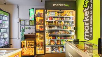 Interior de um supermercado com diversos produtos nas prateleiras e uma área refrigerada.