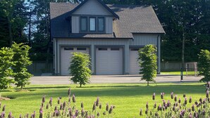 A two-story house with a garage, surrounded by a well-maintained lawn and purple flowers.