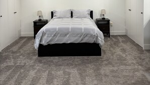 A bedroom with a bed, nightstands, a ceiling fan, and a sloped ceiling.