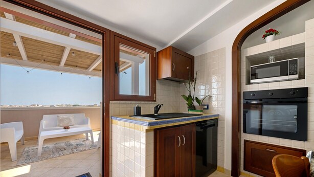 A compact kitchen with a built-in microwave, oven, and sink. - AgoRattico – Elegant Penthouse with Panoramic Terrace (Quartu Sant'Elena)