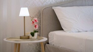 A bedside table with a lamp, a potted orchid, and a small decorative item. - AgoRattico – Elegant Penthouse with Panoramic Terrace (Quartu Sant'Elena)