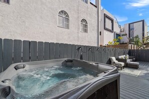 Ein Whirlpool auf einer Holzterrasse, im Hintergrund ein Haus.