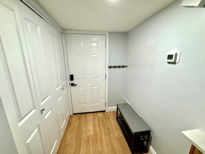 A hallway with a bench, a coat rack, and a door. - Snowbird Escape: Turnkey 2BR Naples Condo with Golf Views & Screened Lanai (Naples)