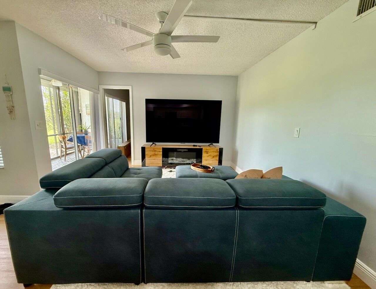 A modern living room with a sectional sofa, a flat-screen TV, and a fireplace.
