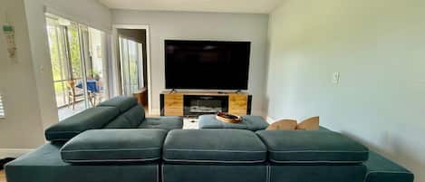 A modern living room with a sectional sofa, a flat-screen TV, and a fireplace.