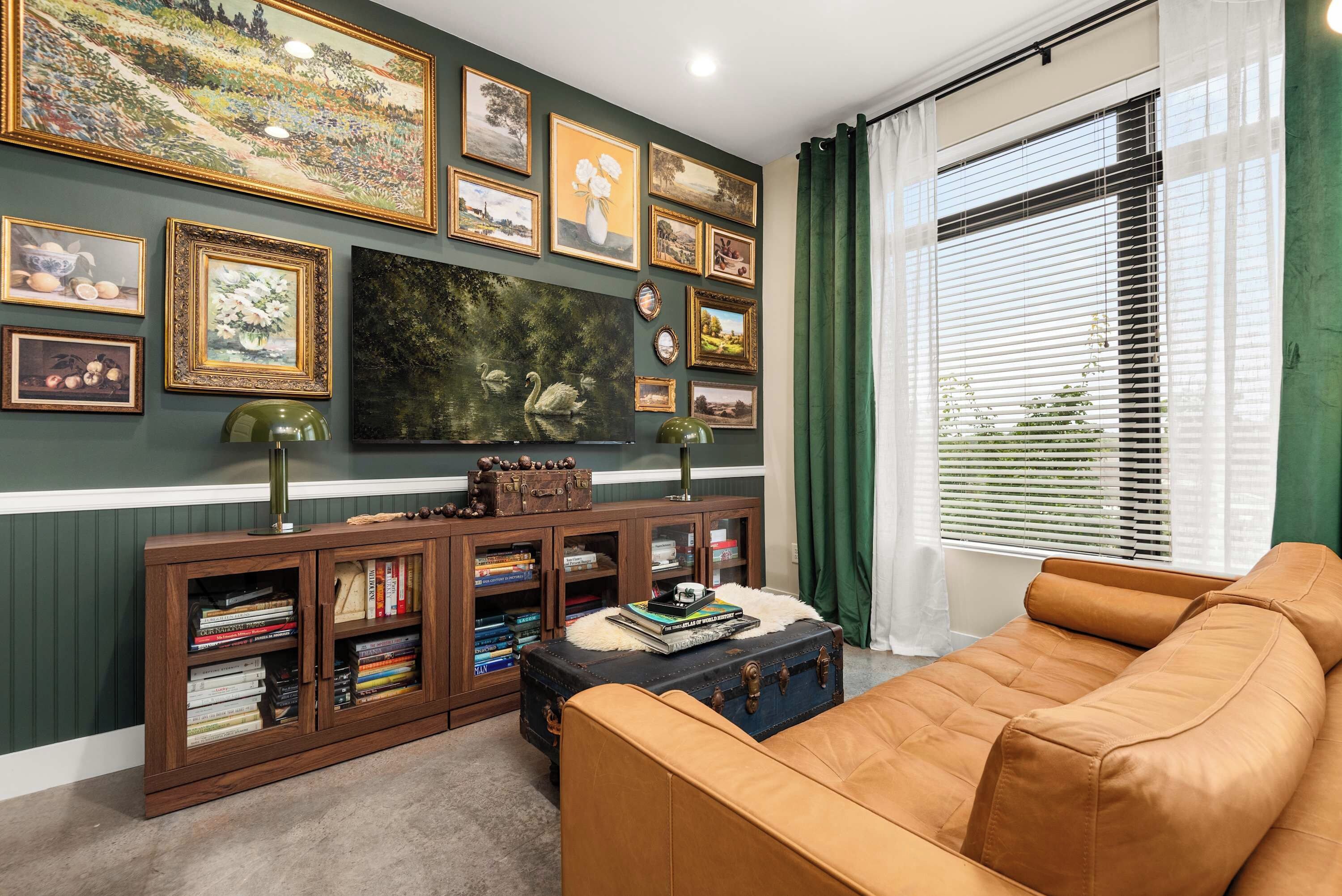 A living room with a brown leather sofa, a wooden bookshelf, and a large flat-screen TV mounted on the wall.