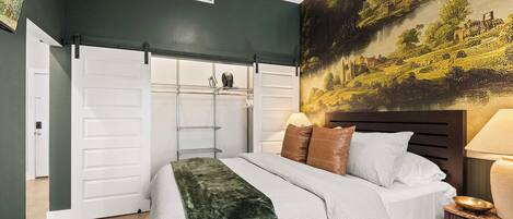 A bedroom with a bed, a nightstand, a lamp, a painting on the wall, and a sliding closet door.