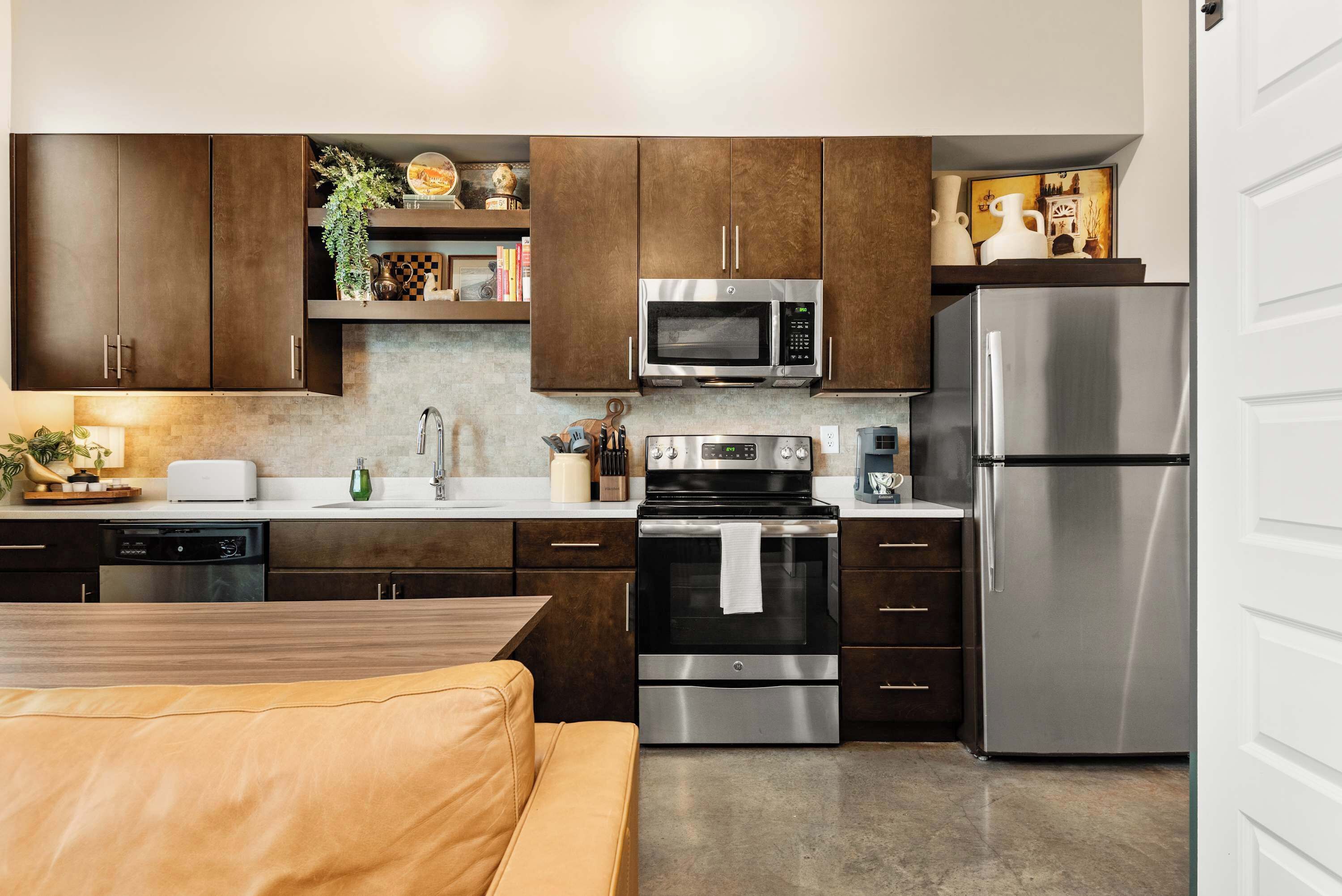Una cocina moderna con electrodomésticos de acero inoxidable, armarios de madera y un comedor con sofá de cuero.