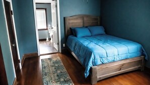 Ein Schlafzimmer mit einem hölzernen Bett, einer blauen Bettdecke und einem Holzboden.