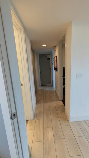 A hallway with light-colored wooden flooring, white walls, and doors on both sides. - Bentonville Basecamp Bike-Friendly Near Downtown & Crystal Bridges (Bentonville)