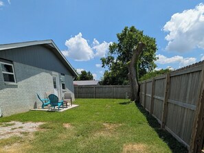 A residential backyard with a house, a wooden fence, a tree, and outdoor furniture. - Bentonville Basecamp Bike-Friendly Near Downtown & Crystal Bridges (Bentonville)
