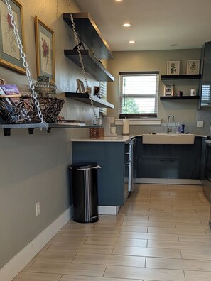 A modern kitchen with a built-in island, stainless steel appliances, and a window providing natural light. - Bentonville Basecamp Bike-Friendly Near Downtown & Crystal Bridges (Bentonville)