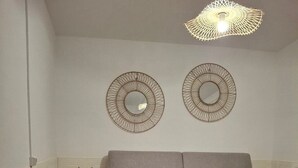 Ein Wohnzimmer mit grauem Sofa, einem weißen Couchtisch, einer Bank und zwei Wandspiegeln.