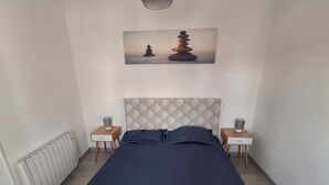 Ein Schlafzimmer mit einem Bett, zwei Nachttischen, einem Heizkörper und einem Bild von gestapelten Steinen.