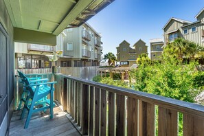 A wooden deck with a view of multi-story buildings and greenery.