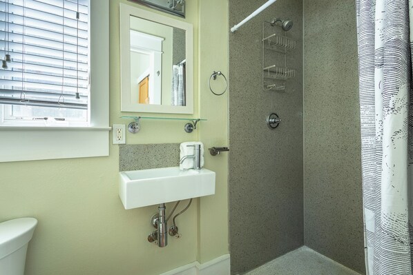 Une salle de bain avec une douche, un lavabo et un miroir.