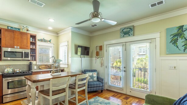 A kitchen with a dining area, a ceiling fan, and a view through the sliding glass door. - Cozy Condo with River views (Carrabelle)