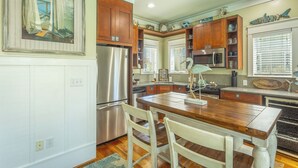 A kitchen with wooden cabinets, stainless steel appliances, and a dining area with a wooden table and chairs. - Cozy Condo with River views (Carrabelle)