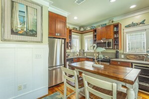 A kitchen with wooden cabinets, stainless steel appliances, and a dining area with a wooden table and chairs.
