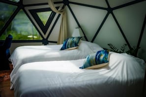 A room with two beds, each with a pillow, a window, and a plant. - Munaya Resort (Marshall)