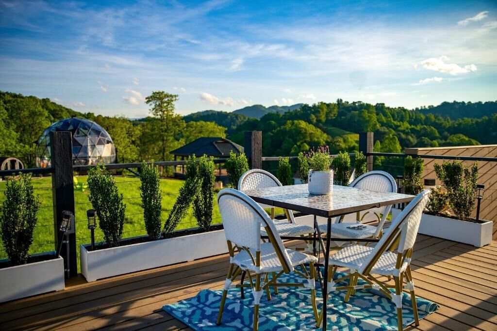An outdoor deck with a table and chairs, overlooking a green landscape.