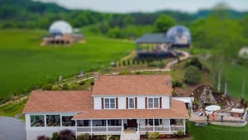 A model of a house with a porch, surrounded by a green landscape and two dome structures in the background.