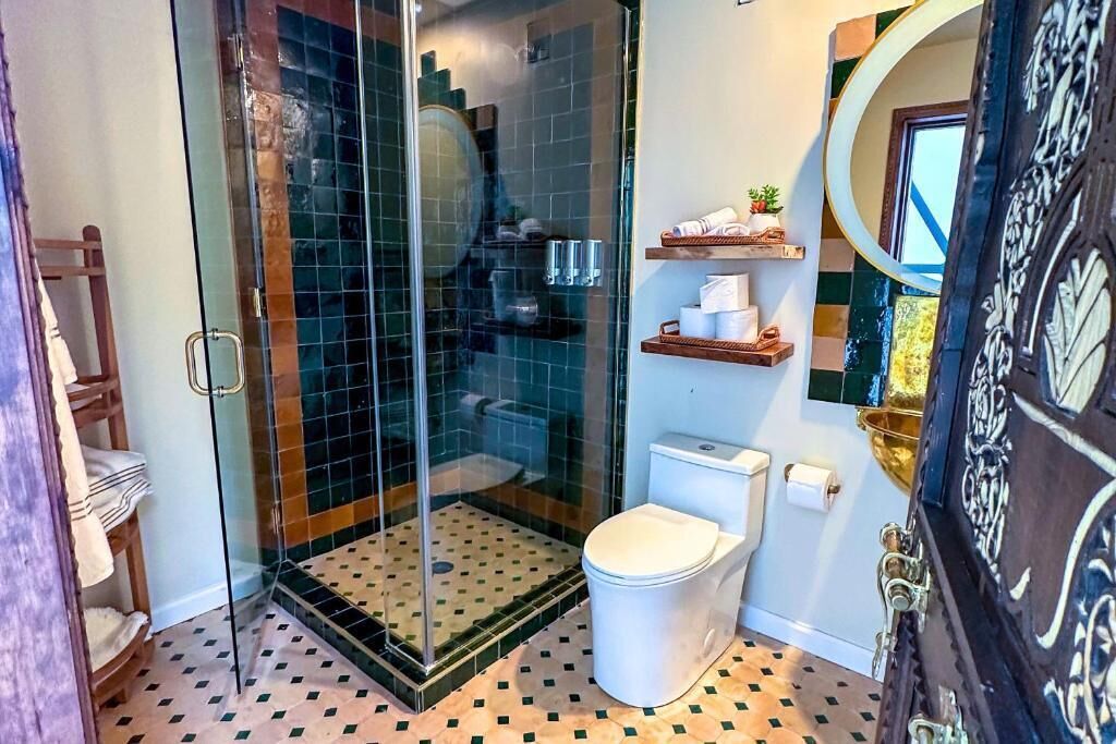 Une salle de bain avec une douche à parois de verre, des toilettes et une étagère contenant des articles de toilette.