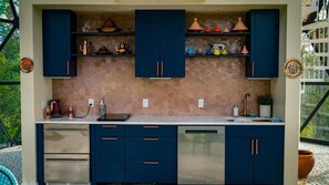 Una cocina con armarios azul oscuro, lavavajillas y salpicadero de azulejos.
