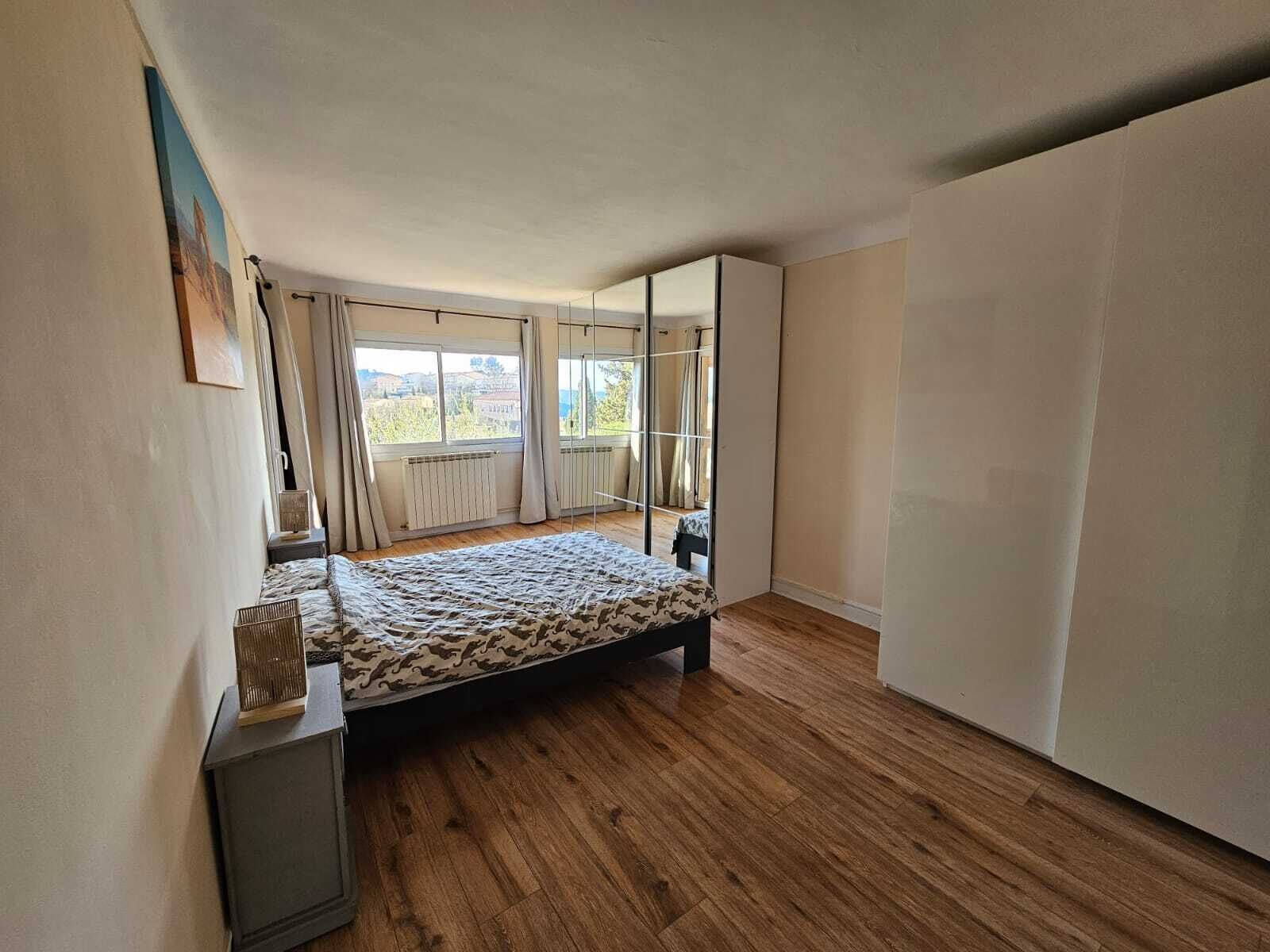 Une chambre à coucher avec un lit, une armoire, un radiateur et une fenêtre avec des rideaux.
