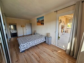 Ein Schlafzimmer mit einem Bett, einem Nachttisch, einem Gemälde und einer Schiebetür zum Balkon.